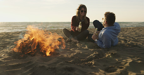 Image showing Loving Young Couple Sitting On The Beach beside Campfire drinkin