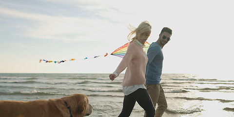 Image showing couple with dog having fun on beach on autmun day