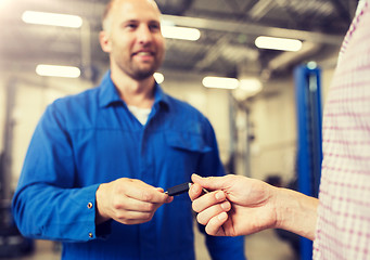 Image showing auto mechanic giving car key to man at workshop