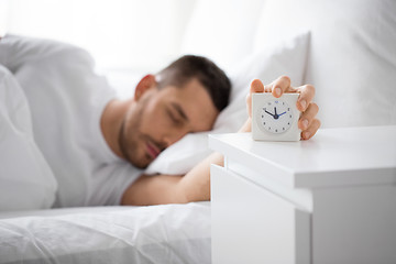 Image showing close up of man in bed reaching for alarm clock