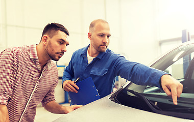 Image showing auto mechanic with clipboard and man at car shop