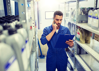 Image showing auto mechanic calling on smartphone at car shop