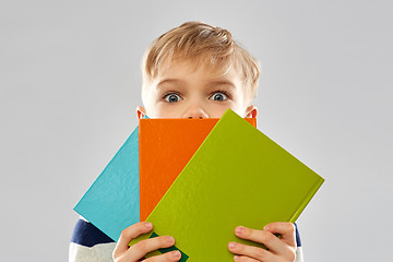 Image showing shy schoolboy hiding behind books
