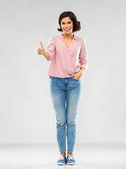 Image showing young woman in shirt and jeans showing thumbs up