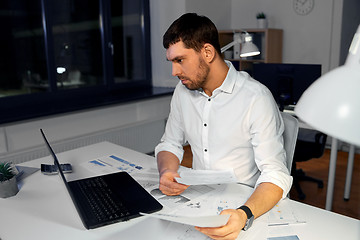 Image showing businessman with papers and laptop at night office