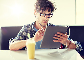 Image showing man with tablet pc and earphones sitting at cafe