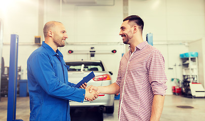 Image showing auto mechanic and man shaking hands at car shop