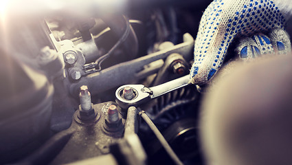 Image showing mechanic man with wrench repairing car at workshop