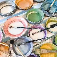 Image showing Paint brushes in colorful ceramic plates