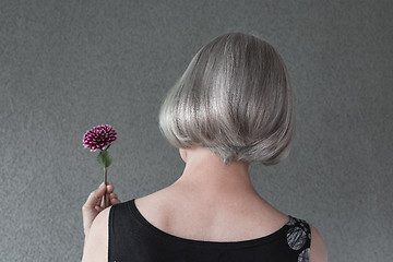 Image showing Gray-haired lady holding red dahlia