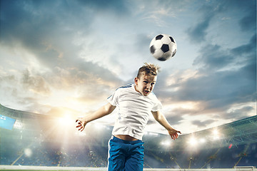 Image showing Young boy with soccer ball doing flying kick at stadium