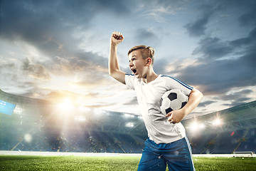 Image showing Young boy with soccer ball doing flying kick at stadium