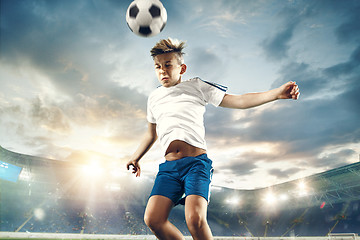 Image showing Young boy with soccer ball doing flying kick at stadium