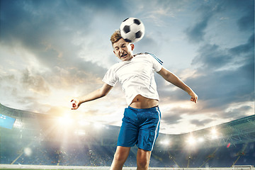 Image showing Young boy with soccer ball doing flying kick at stadium