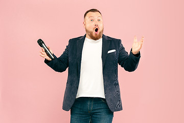 Image showing Young man with microphone on pink background, leading with microphone