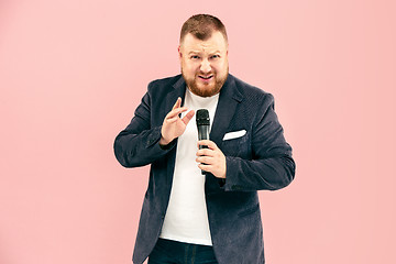 Image showing Young man with microphone on pink background, leading with microphone