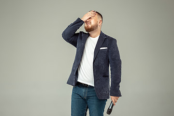 Image showing Young man with microphone on gray background, leading with microphone