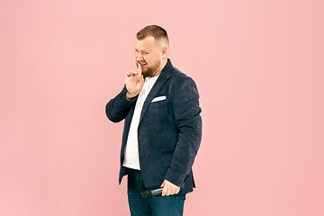 Image showing Young man with microphone on pink background, leading with microphone