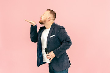 Image showing Young man with microphone on pink background, leading with microphone