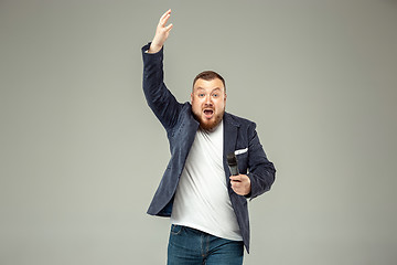 Image showing Young man with microphone on gray background, leading with microphone