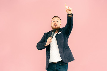 Image showing Young man with microphone on pink background, leading with microphone