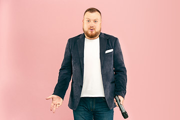 Image showing Young man with microphone on pink background, leading with microphone