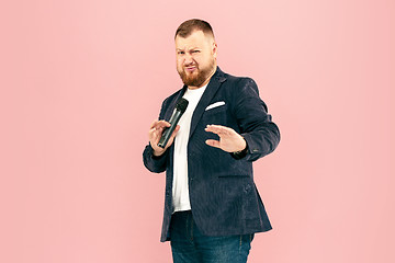 Image showing Young man with microphone on pink background, leading with microphone