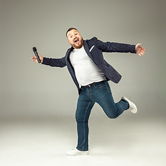 Image showing Young man with microphone on gray background, leading with microphone