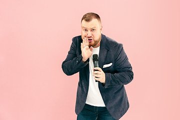 Image showing Young man with microphone on pink background, leading with microphone