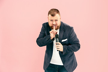 Image showing Young man with microphone on pink background, leading with microphone