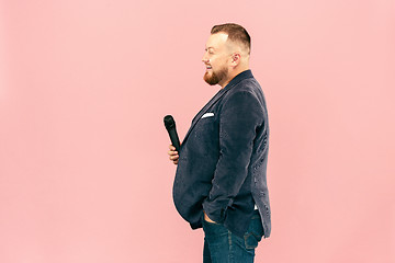 Image showing Young man with microphone on pink background, leading with microphone