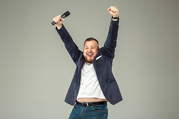 Image showing Young man with microphone on gray background, leading with microphone