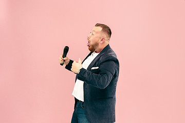 Image showing Young man with microphone on pink background, leading with microphone