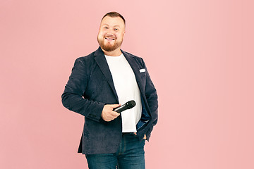 Image showing Young man with microphone on pink background, leading with microphone