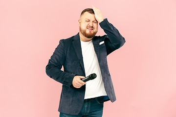 Image showing Young man with microphone on pink background, leading with microphone