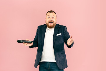 Image showing Young man with microphone on pink background, leading with microphone