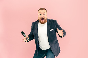 Image showing Young man with microphone on pink background, leading with microphone