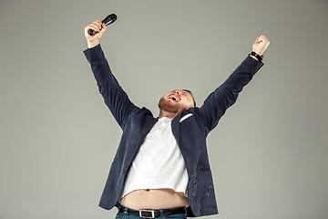 Image showing Young man with microphone on gray background, leading with microphone