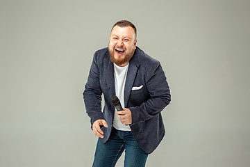 Image showing Young man with microphone on gray background, leading with microphone