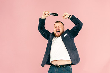 Image showing Young man with microphone on pink background, leading with microphone