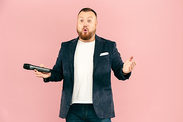 Image showing Young man with microphone on pink background, leading with microphone