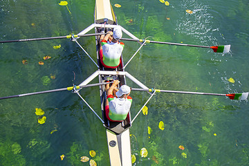 Image showing Two young athletes rowing team on green lake