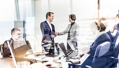 Image showing Confident business people shaking hands in moder corporate office.