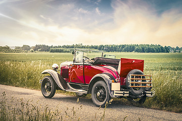 Image showing Antique red car on a road in a countryside landscape