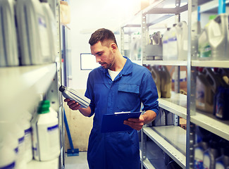 Image showing auto mechanic with oil and clipboard at car shop