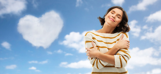 Image showing woman hugging herself over heart shaped cloud