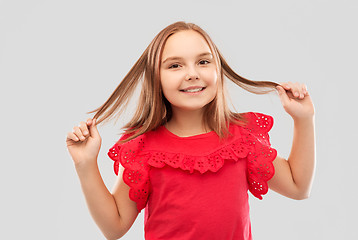 Image showing happy girl in red shirt with holding hair strands