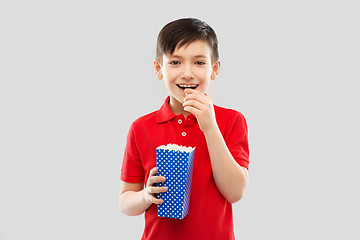 Image showing smiling boy in red t-shirt eating popcorn