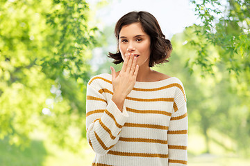 Image showing woman covers mouth by hand over natural background