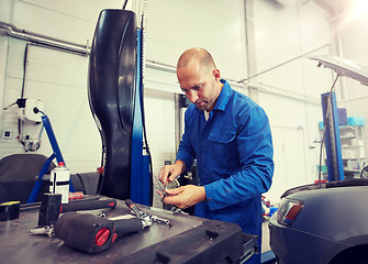 Image showing mechanic man with wrench repairing car at workshop